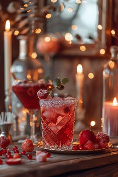 a glass filled with red liquid next to candles and other holiday decorations on a table