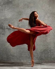 a woman in a red dress is dancing with her legs spread out and arms outstretched