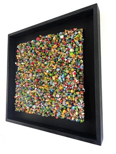 a black framed art piece with many small objects on it's sides and bottom