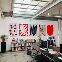 an office with multiple desks and bookshelves filled with various types of art