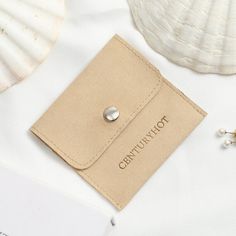 a card case with a button on it next to some seashells