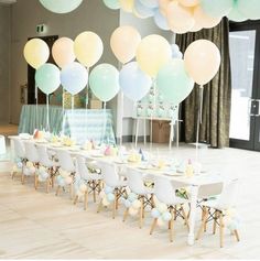 a table set up for a baby shower with pastel balloons