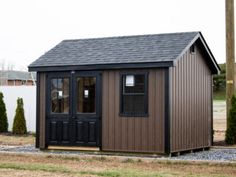 a small brown shed sitting on top of a grass covered field