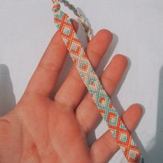 a hand holding an orange and blue bracelet