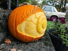 a pumpkin carved to look like an eyeball sitting on the side of a road