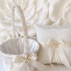 two white wedding baskets with satin ribbons and bows on the side, sitting next to each other