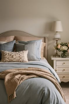 a bedroom with a bed, nightstand and flowers on the side table in front of it