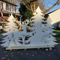 a white wooden christmas tree sitting in front of a house