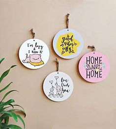 four different colored ceramic ornaments hanging on a wall next to a potted green plant