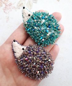 two brooches in the shape of hedgehogs are sitting on someone's hand