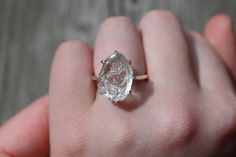 a close up of a person's hand holding a ring with a diamond in it