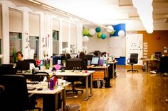 an office filled with desks and chairs next to each other on hard wood floors