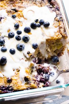 a blueberry cobbler is shown in a glass casserole dish with a spoon