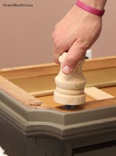 a person's hand holding a piece of wood on top of a dresser drawer