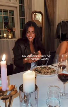 a woman sitting at a table in front of a plate of food with candles on it