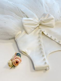 a white wedding garter with a flower on the side and a pin attached to it