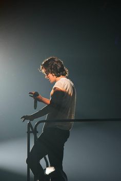 a young man sitting on top of a metal chair in front of a spotlight light