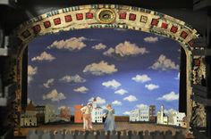 two people standing on a stage in front of a blue sky with clouds and buildings