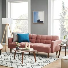 a living room filled with lots of furniture next to two large windows and a rug on the floor