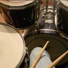 a person with their feet up in front of drum sticks and drumsticks on the floor