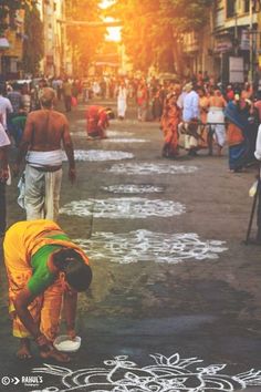 a woman kneeling down in the middle of a street with chalk drawings on the ground