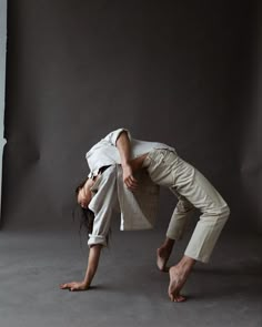 a woman in white shirt and pants doing a handstand on the ground with her legs crossed