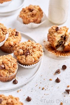 several muffins with chocolate chips on a plate next to a glass of milk