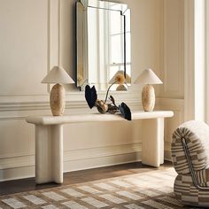 a white table topped with two lamps next to a mirror and chair in a room