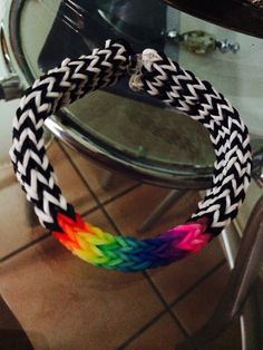 a rainbow colored bracelet sitting on top of a table next to a glass vase and mirror