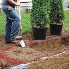 a man is shoveling dirt in front of some potted plants on the ground