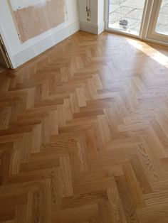 an empty room with wooden floors and large windows