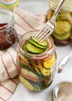 pickled cucumbers are in a jar with a fork