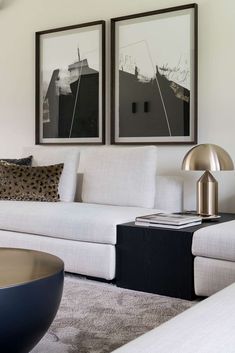 a living room with two pictures hanging on the wall and a white couch in front of it