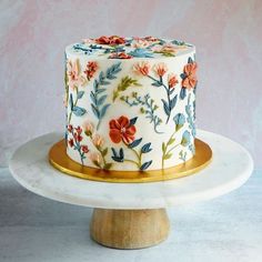 a decorated cake sitting on top of a white plate next to a wooden stand with gold trim