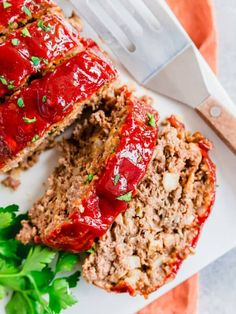 meatloaf with ketchup and parsley on a plate next to a knife