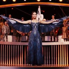 a woman standing on top of a stage wearing a blue dress