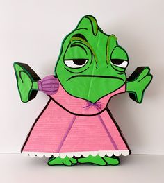 an origami cut out of a green creature wearing a pink dress