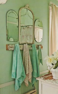 a bathroom with green walls and towels hanging on the wall next to a white cabinet