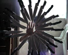 a man is holding his hands in the middle of a large circular arrangement of knives