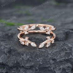 a rose gold ring with three small white diamonds on top of a black stone surface