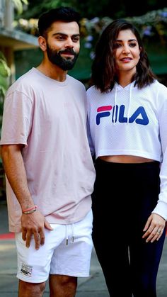 a man and woman standing next to each other in front of a building with the word fila on it