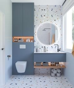 the bathroom is decorated in blue and white with gold dots on the wall, along with a round mirror above the sink