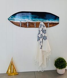 a surfboard hanging on the wall next to a potted plant and towel rack