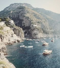 many boats are in the water near some cliffs