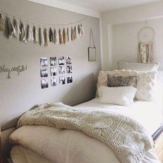 a white bed sitting in a bedroom next to a wall with pictures hanging on it