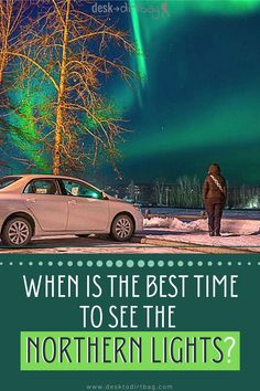 a car parked on the side of a road next to a tree with an aurora light in the background