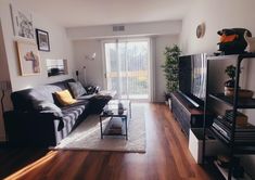 a living room filled with furniture and a flat screen tv sitting on top of a wooden floor