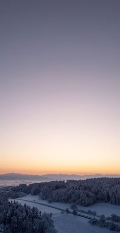 the sun is setting over a snowy landscape