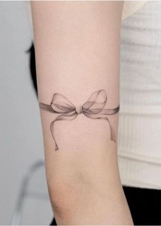 a woman's arm with a bow tattoo on it