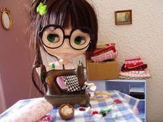 a doll sitting on top of a table with a sewing machine in front of her